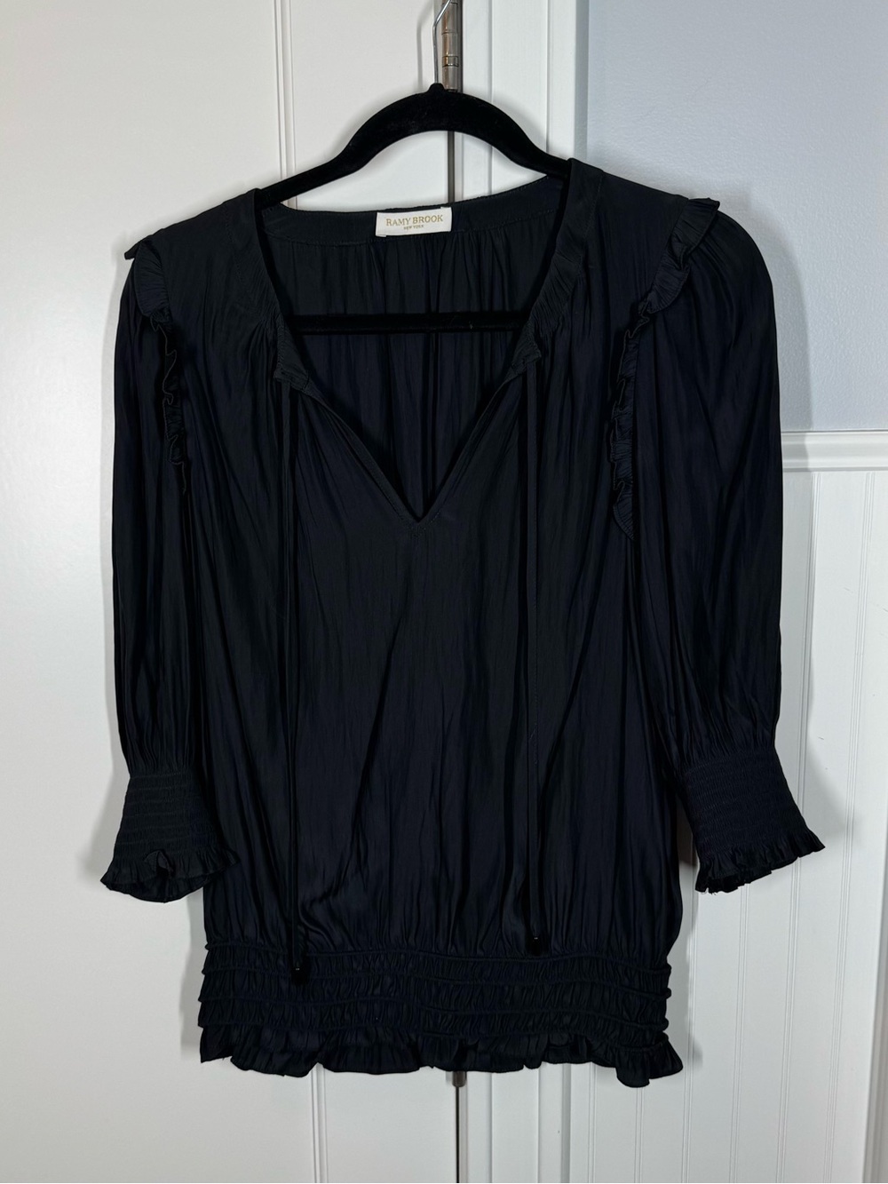 Ramy Brook black blouse featuring a V-neckline, smocked hem ruffled detailing